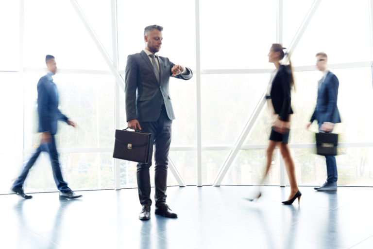 Job candidate waiting for an answer with 3 people walking in the background of an office